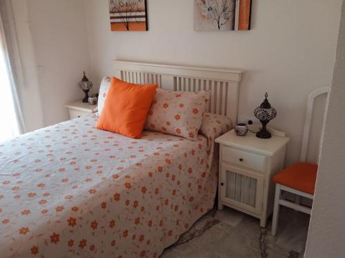 奇克拉纳－德拉弗龙特拉Apartamento La Caracola的一间卧室配有一张带橙色枕头和床头柜的床