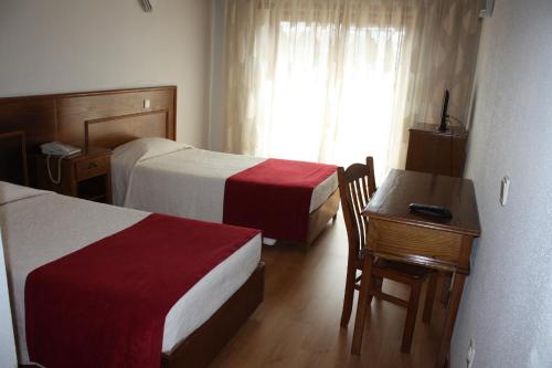 布拉干萨克拉西斯酒店的酒店客房设有两张床、一张书桌和一个窗户。