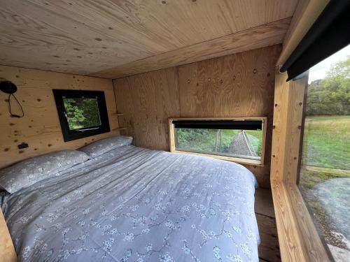 海斯廷斯Hop and hare farm的木制客房的一张床位,设有窗户