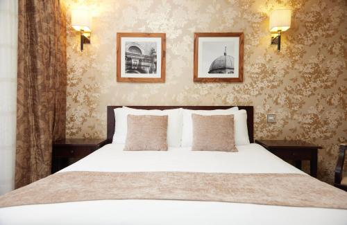 沃本The Bell Hotel Woburn By Greene King Inns的卧室配有白色的床和墙上的两张照片