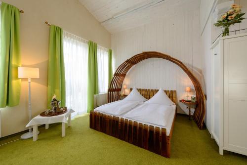 梅森Hotel Wellness Goldenes Fass Meißen的一间卧室配有一张大床和柳条拱门