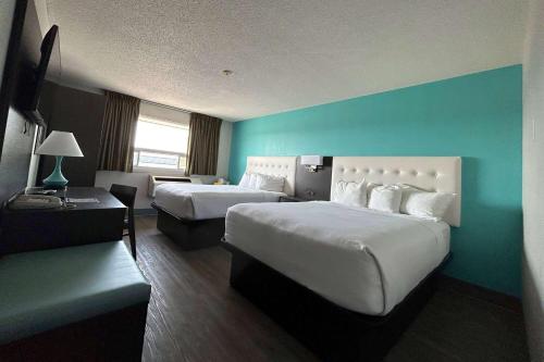 桑德贝Howard Johnson by Wyndham Thunder Bay的酒店客房设有两张床和蓝色的墙壁。