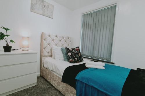 达特福德Saint Johns 3-bedroom House-Greater London的一间卧室配有一张床、一个梳妆台和一扇窗户。