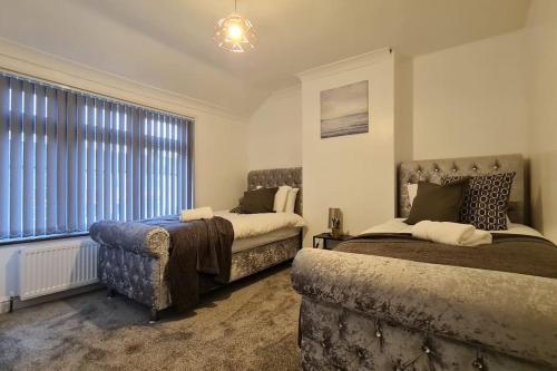 达特福德Saint Johns 3-bedroom House-Greater London的一间卧室设有两张床、一张沙发和一个窗口