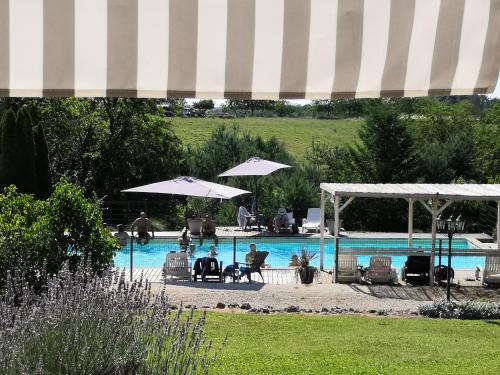 Saint-Julien-de-BourdeillesCAMPING HERMITAGE DES 4 SAISONS的游泳池配有椅子和遮阳伞,旁边的人坐在游泳池旁