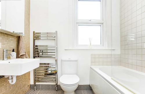 伦敦Bright and Stylish 2 Bedroom First Floor Flat的浴室配有卫生间、盥洗盆和浴缸。