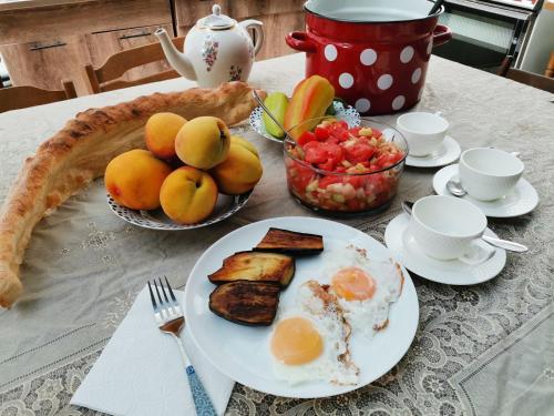 第比利斯EUROPEAN Backpackers Hostel的一张桌子,早餐包括鸡蛋烤面包和水果