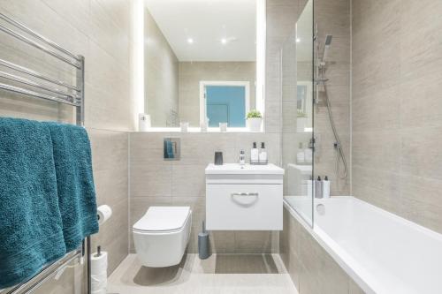 米尔顿凯恩斯Elegant apartment的浴室配有卫生间、浴缸和水槽。