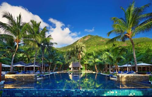 锡卢埃特岛塞舌尔拉布里兹希尔顿度假及Spa酒店的棕榈树和山底下的游泳池