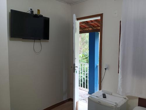 莫埃达Pousada Maravilhas da Serra的一间墙上配有电视的房间和一个卫生间