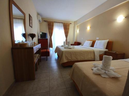 LágosPorto Vistonis的酒店客房设有两张床、一张桌子和一面镜子