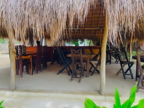 KandakuliThe Crab Beach Resort的稻草屋顶下带桌椅的餐厅