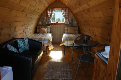 CorscombeKnapp Farm Glamping Puki Pod的小屋内带两张床和一张沙发的房间