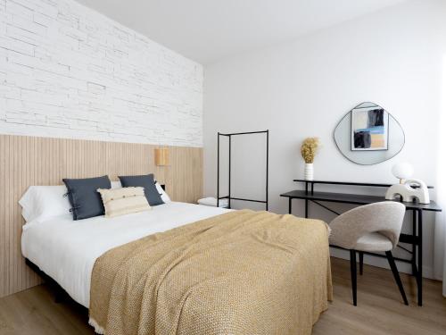 阿斯托加Meraki Suites的一间卧室配有一张床、一张书桌和一面镜子