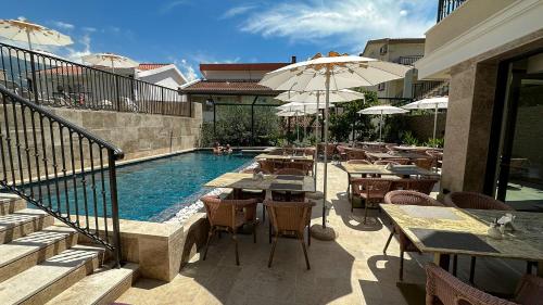 布德瓦Hotel Pima Budva的餐厅旁的游泳池配有桌子和遮阳伞
