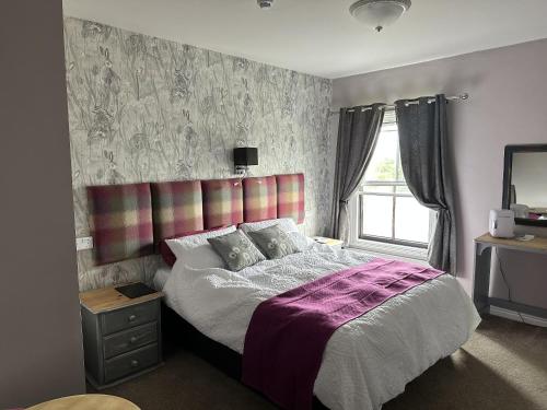AlburghThe Dove Inn的一间卧室设有一张大床和一个窗户。