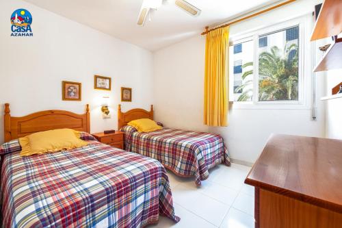 阿尔考斯布里Apartamentos La Noria Casa Azahar的一间卧室设有两张床和窗户。