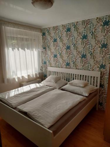 豪伊杜索博斯洛埃列克公寓式酒店的卧室内的一张白色大床,配有花卉壁纸