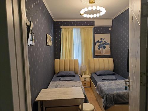第比利斯Hotel Lilo near Airport的一间卧室设有两张床、一张桌子和一个窗口