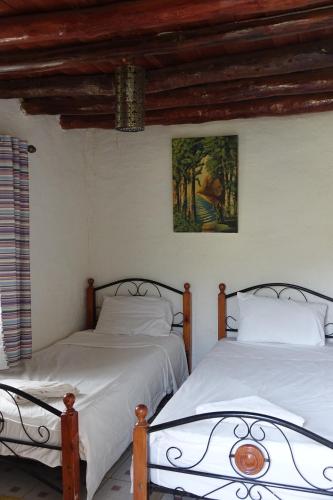 Aïn Bou MahdiRelais De Tahla的卧室内的两张床,墙上有绘画作品