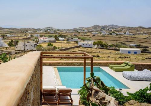 阿诺梅拉Myconian Mythodea Luxury Villa的一个带椅子的游泳池,享有田野的景色