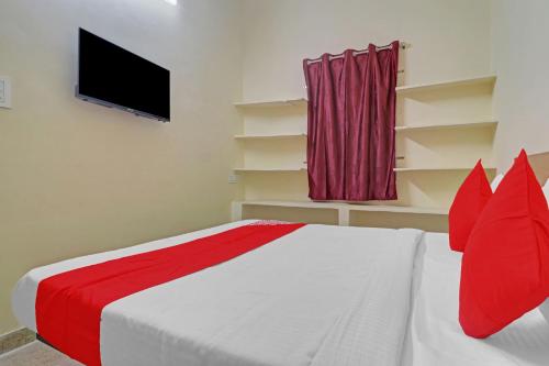 Haidar Sāhibgūda80983G RBS Square Langer Houz的一间卧室配有一张带红色枕头的床和一台电视。