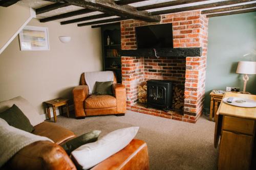 滨海凯斯特Pebbles Cottage的客厅设有砖砌壁炉和电视。