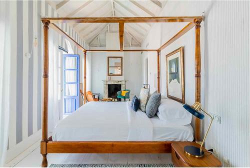 马贝拉The Pearl - Marbella的卧室配有带白色床单的木制天蓬床