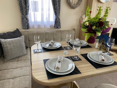 Littlestone-on-SeaComfy Cosy Caravan_Romney Sands的餐桌,配有盘子和酒杯