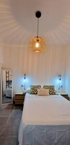 库列拉Loft el Baix - Cullera的卧室配有一张带吊灯的大型白色床。