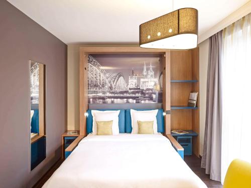 科隆科隆市阿德吉奥公寓式酒店的卧室配有一张大床,墙上挂有绘画作品
