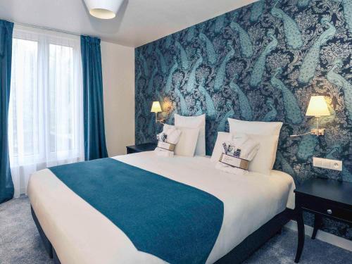 克劳德巴黎圣克卢竞技场美居酒店的酒店客房设有一张大床和壁画