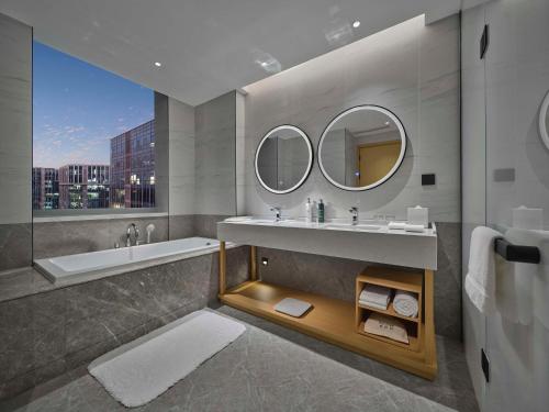 北京北京海淀稻香湖希尔顿花园酒店的一间带水槽、浴缸和镜子的浴室