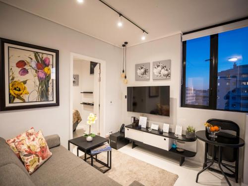 开普敦Flamingo Sea Point Sea View Luxury Best Position 1 Bedroom Apartment Queen Size Bed & Inverter For TV的客厅配有沙发和桌子