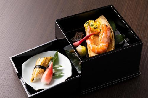 伊东料理の宿　伊豆の花的桌上放有盘子的食物的盒子