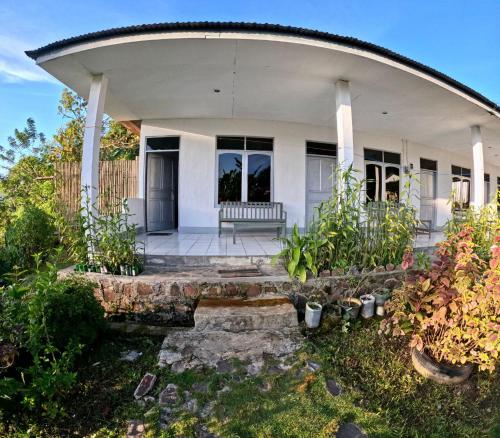 克里穆图Hidayah homestay的白色的房子,有门廊和一些植物