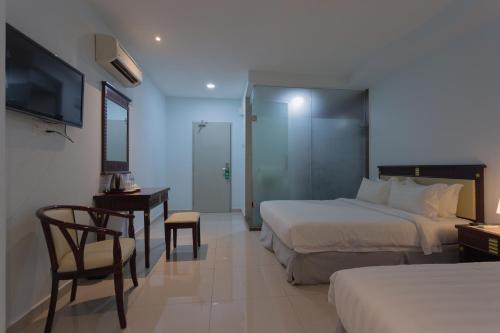吉隆坡Hotel AL Amin的酒店客房设有两张床、一张桌子和一台电视。