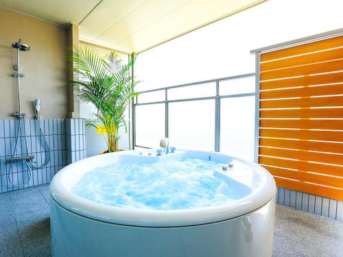 岛原市Hotel Seaside Shimabara的一间带大窗户的浴室内的大浴缸