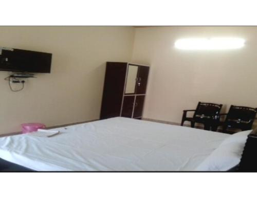 KushinagarHotel Mamta Palace, Kushinagar的一间卧室配有一张带椅子的床和电视