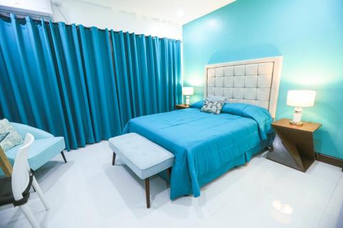 IsabelThe Suites @ Bellavista的蓝色卧室,配有床和椅子