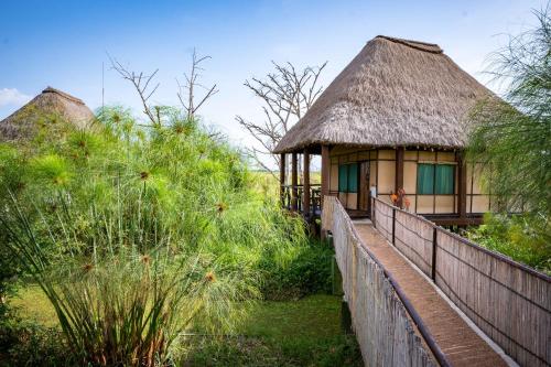 ItongaLittle Okavango Camp Serengeti, A Tent with a View Safaris的茅草屋顶和围栏的小小屋