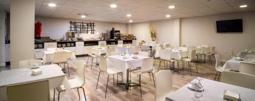 韦尔瓦Hotel Familia Conde的用餐室配有白色的桌子和白色的椅子