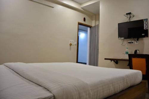 加尔各答Hotel Royal Residency的一间卧室配有一张床和一台平面电视