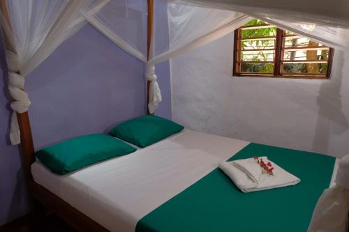 Nosy KombaVilla Ilo Komba的一张带绿色枕头的白色床和窗户
