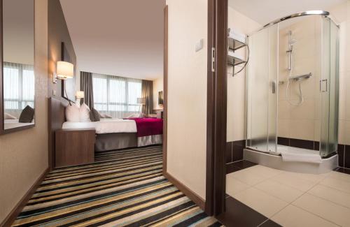 华沙华沙莱昂纳多皇家酒店的带淋浴和床的酒店客房