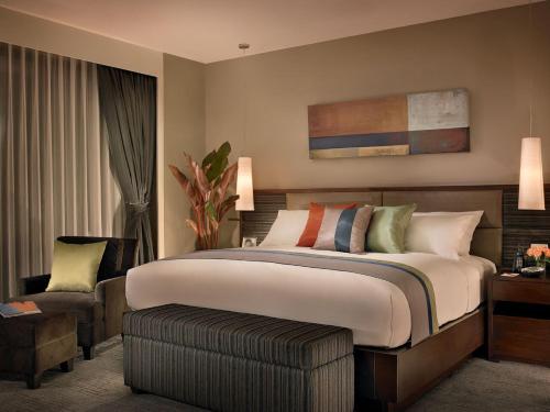 曼谷邦纳自豪公寓式酒店的一间卧室配有一张大床和一把椅子