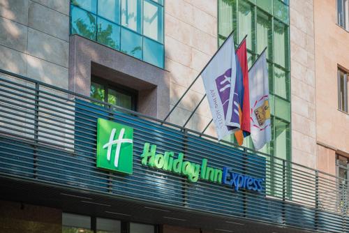 埃里温Holiday Inn Express - Yerevan, an IHG Hotel的标志,标志上悬挂着旗帜的建筑物