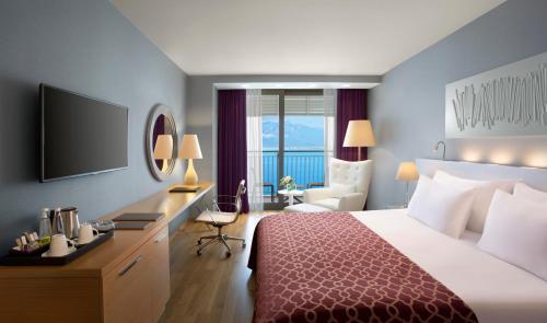 安塔利亚Akra Antalya的酒店客房配有一张床、一张书桌和一台电视。
