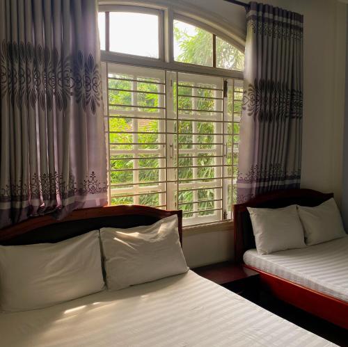 岘港Salyna Motel的卧室在窗户前配有两张床