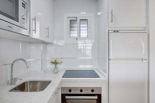 多列毛利诺斯Vistamarina A409 By IVI Real Estate的白色的厨房配有水槽和冰箱